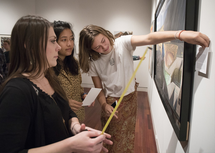 Visiting Assistant Professor Victoria Ehrlich helping to install an exhibition curated by her Intro to Art History students in the Fine Arts Center <span class="cc-gallery-credit"></span>